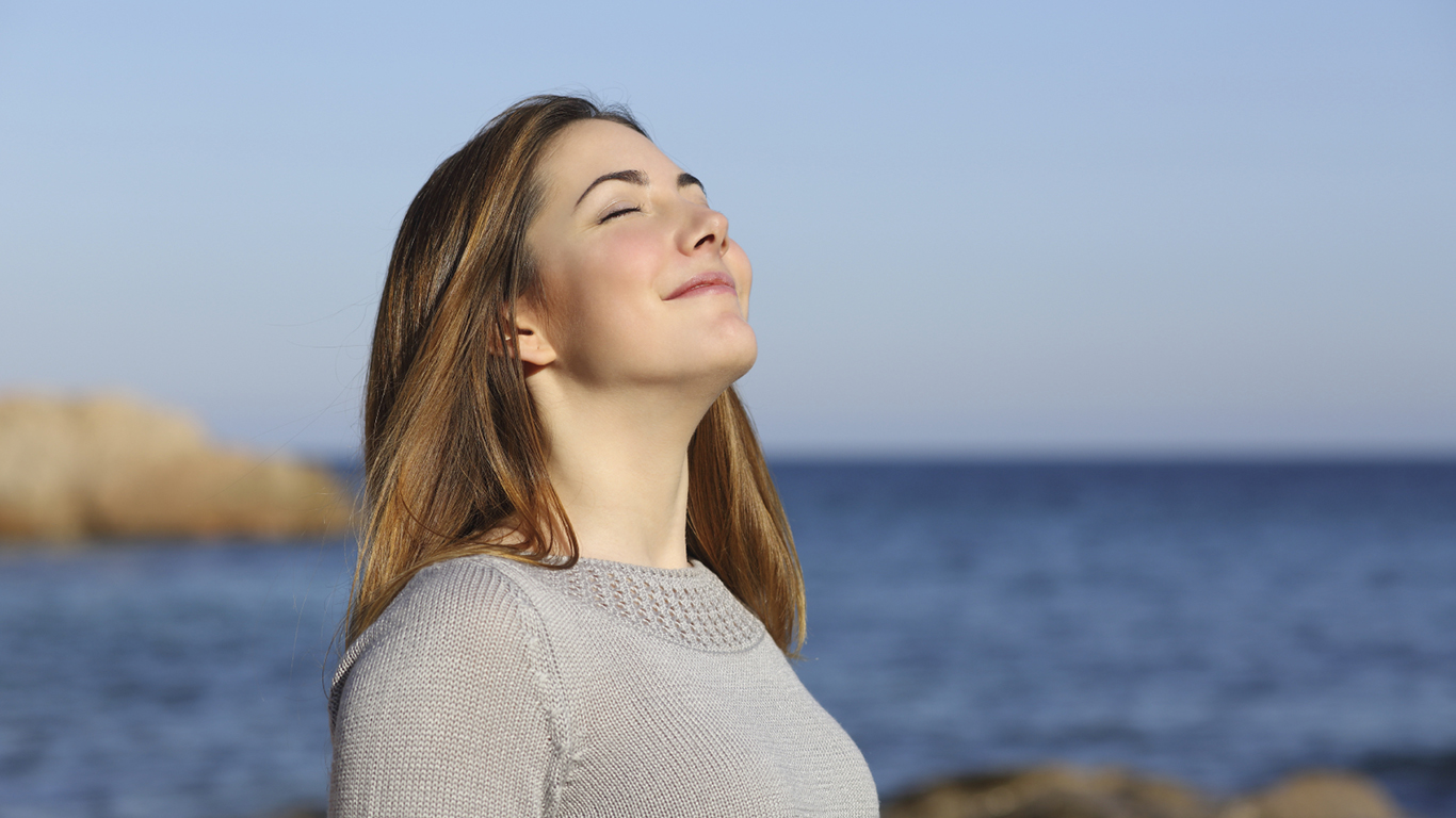 Happy woman breathing deep fresh air on the beach